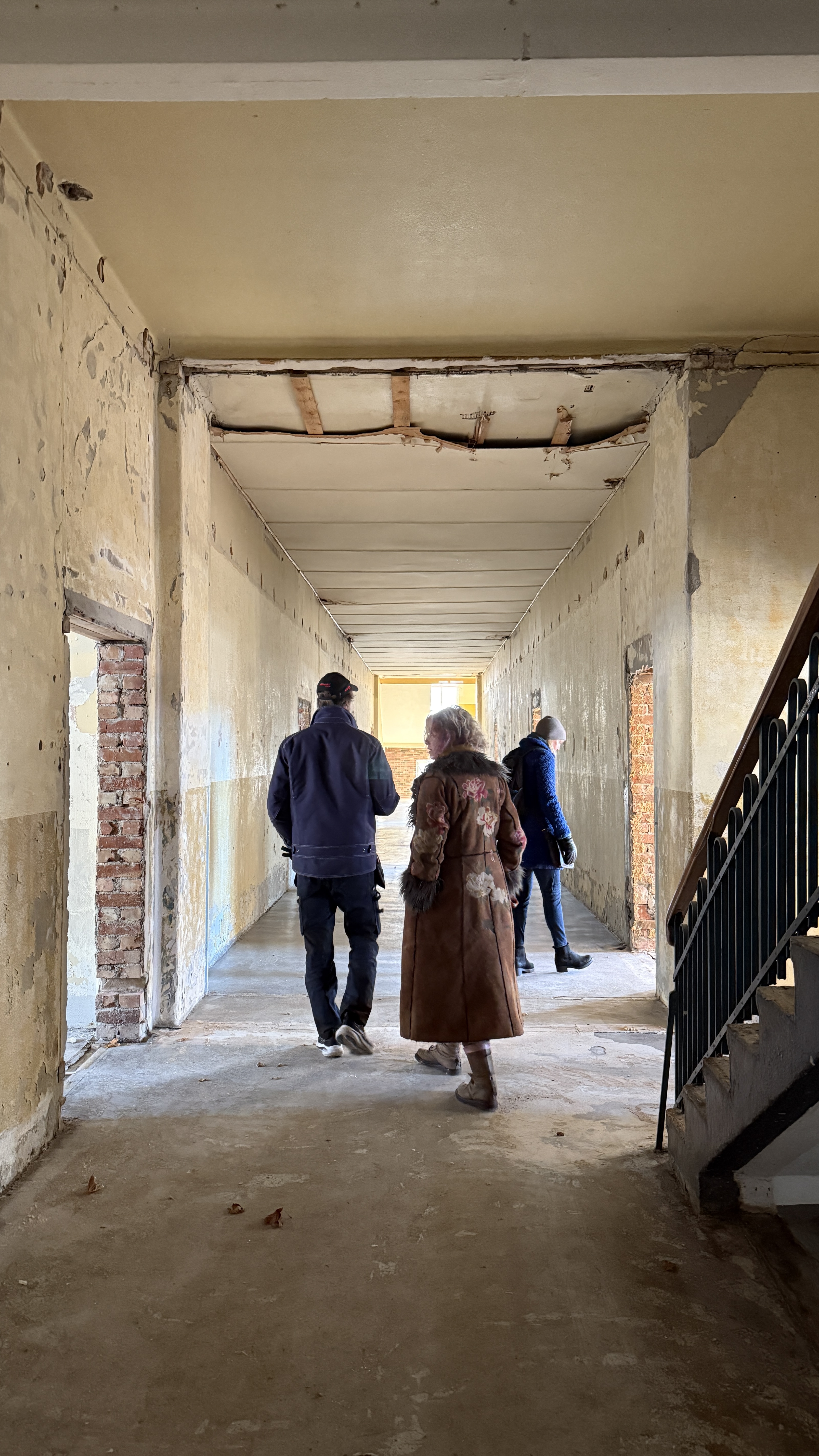 Tre personer går nedover en gang under oppussing