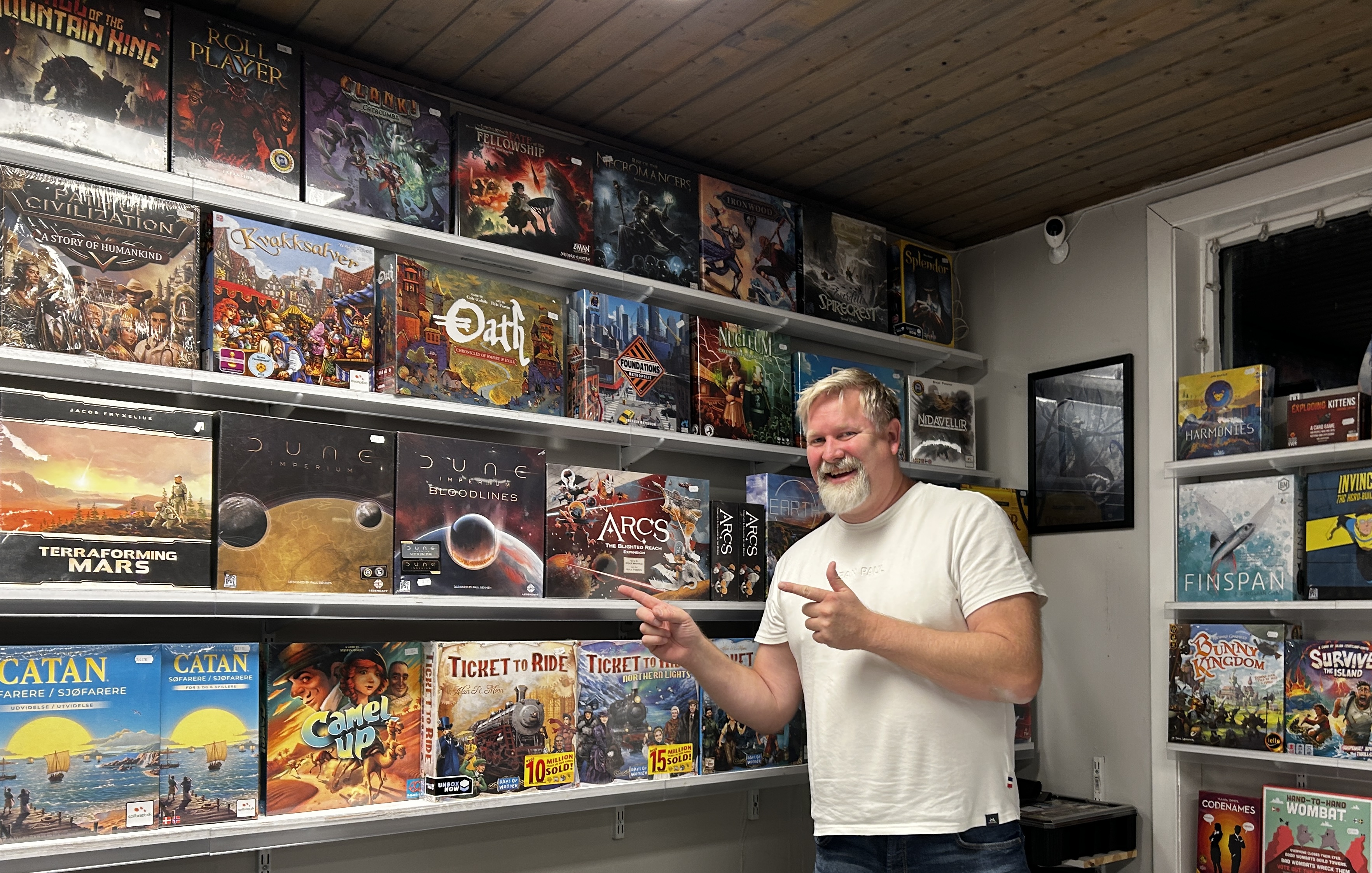 En mann peker på utvalget av brettspill i butikken.